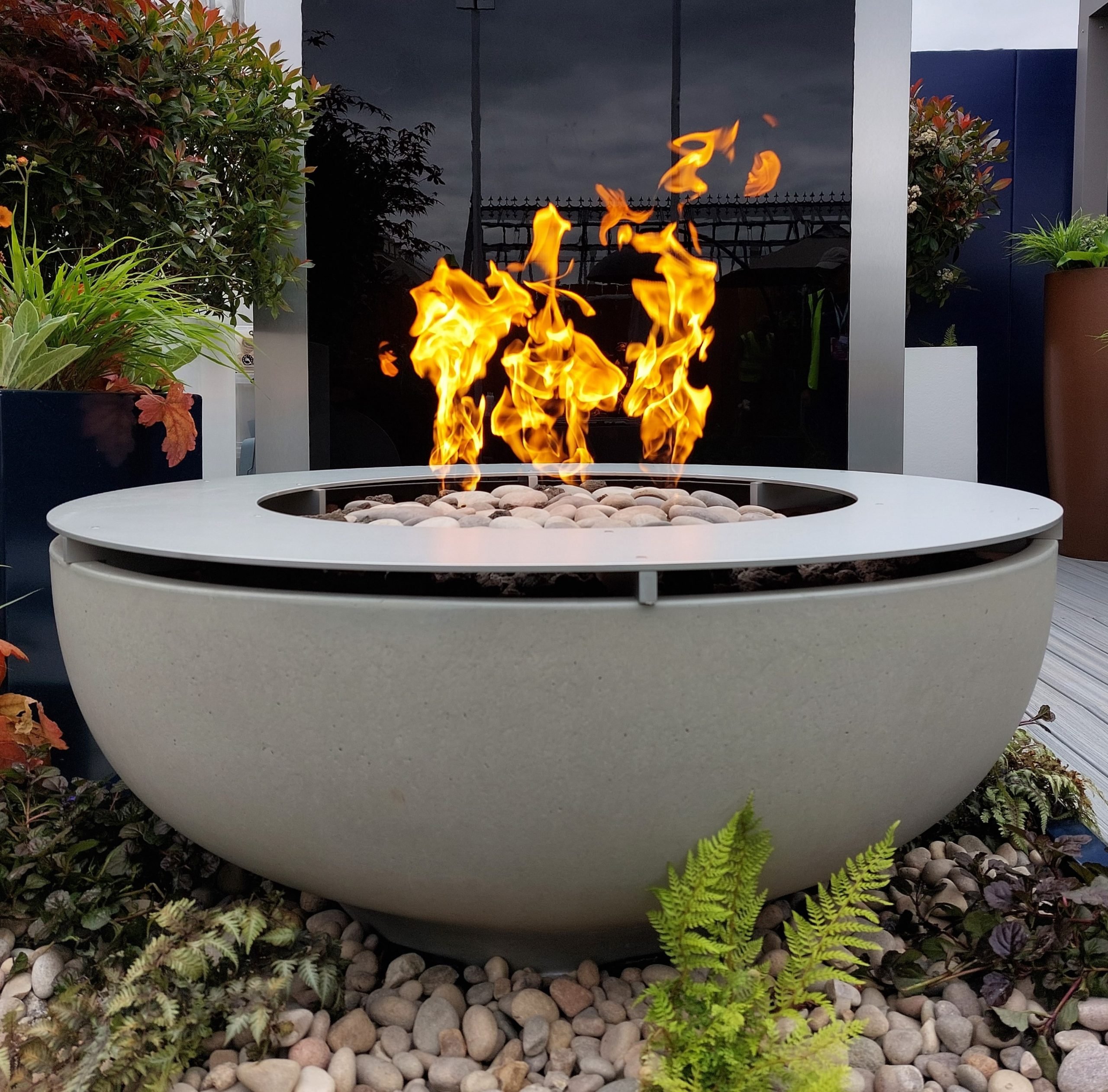 Solus Decor's Luna Fire Bowl - a fire pit with a fire in it, standing on a deck at Chelsea Flower Show 2023 in London