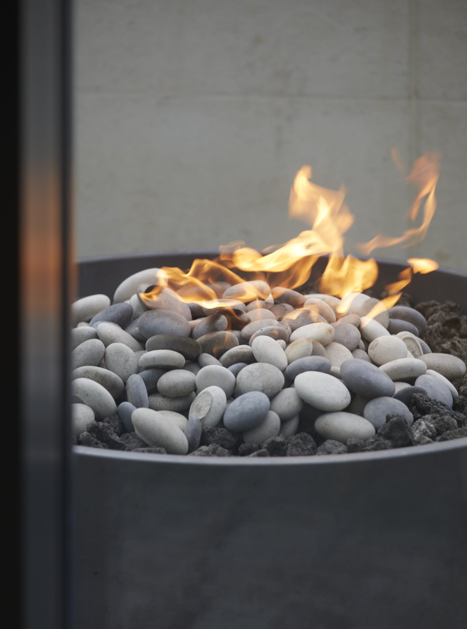 A close up photo of the Solus Decor Hemi Fire Bowl - a fire pit with rocks and a fire twisting around in the wind.